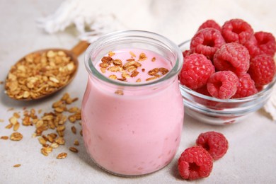 Tasty raspberry smoothie with granola in glass jar and fresh berries on light table, closeup