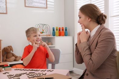 Photo of Speech therapist working with little boy in office