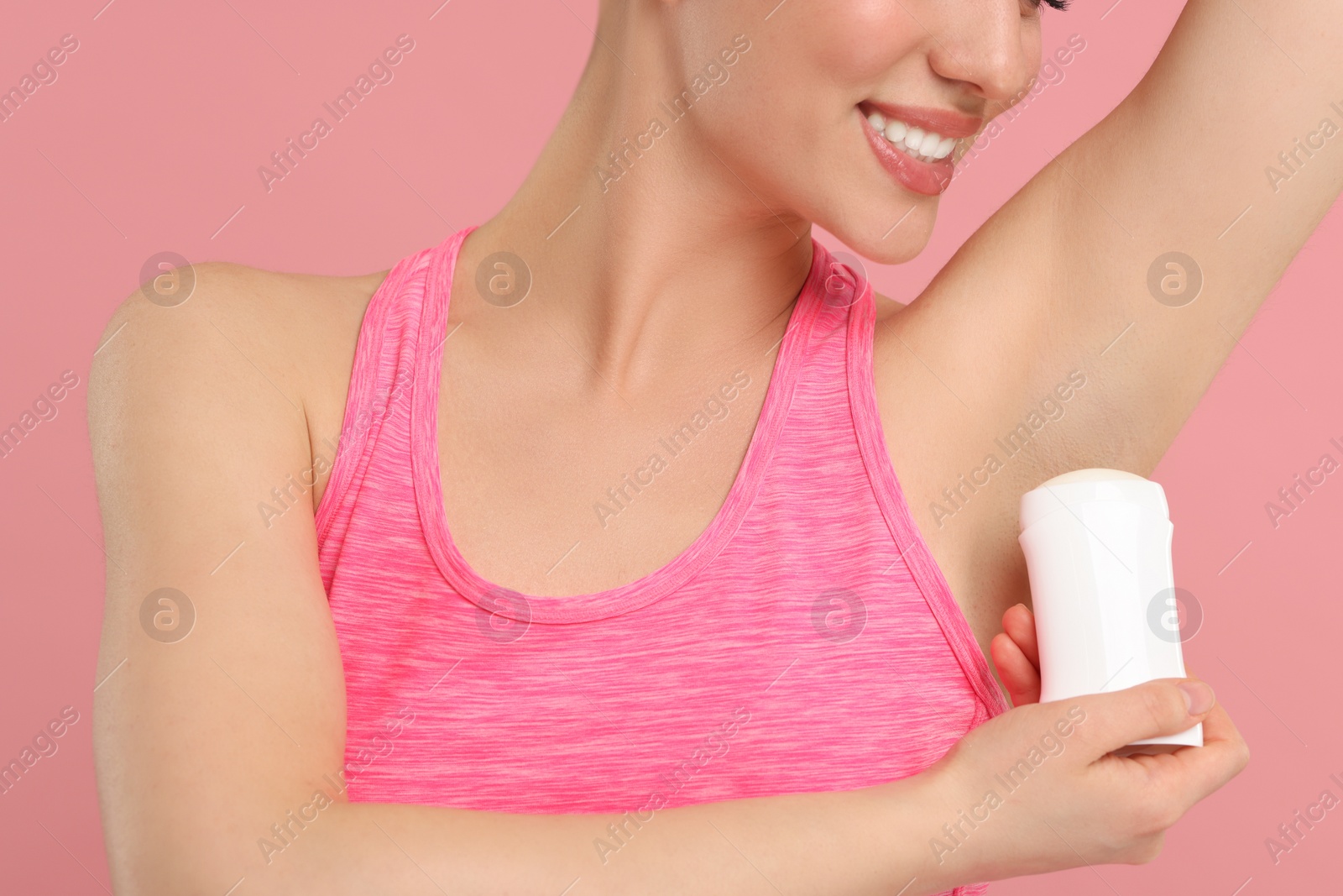 Photo of Woman applying deodorant on pink background, closeup