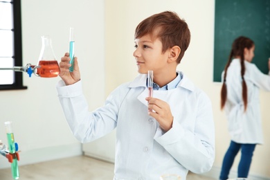 Photo of Smart pupil with test tubes in chemistry class