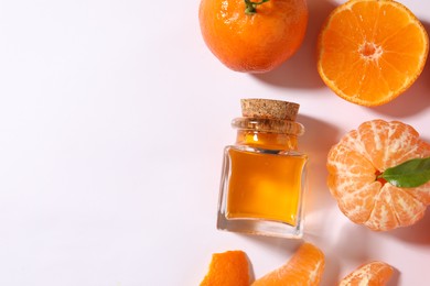 Aromatic tangerine essential oil in bottle and citrus fruits on white table, flat lay. Space for text