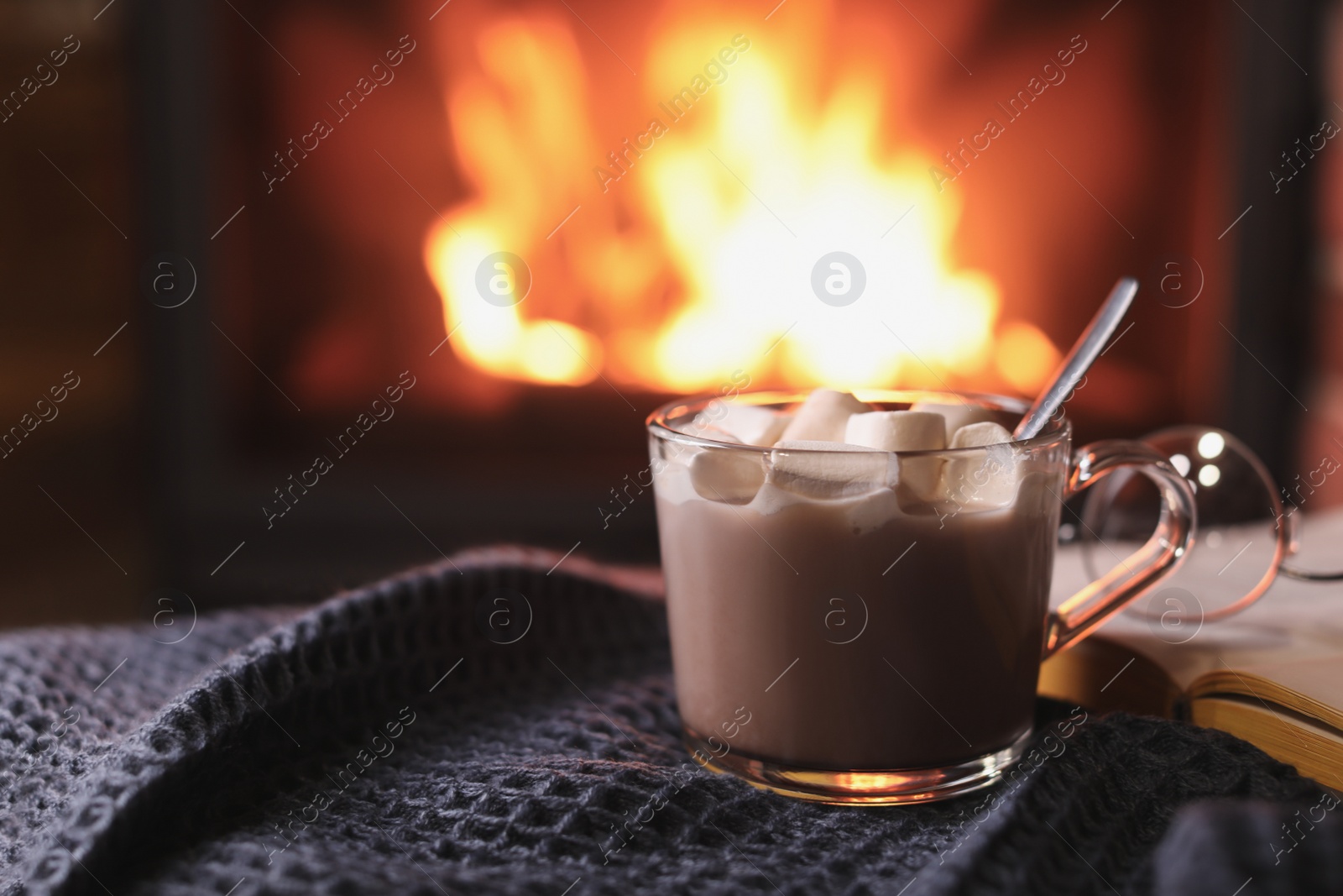 Photo of Delicious sweet cocoa with marshmallows and blurred fireplace on background