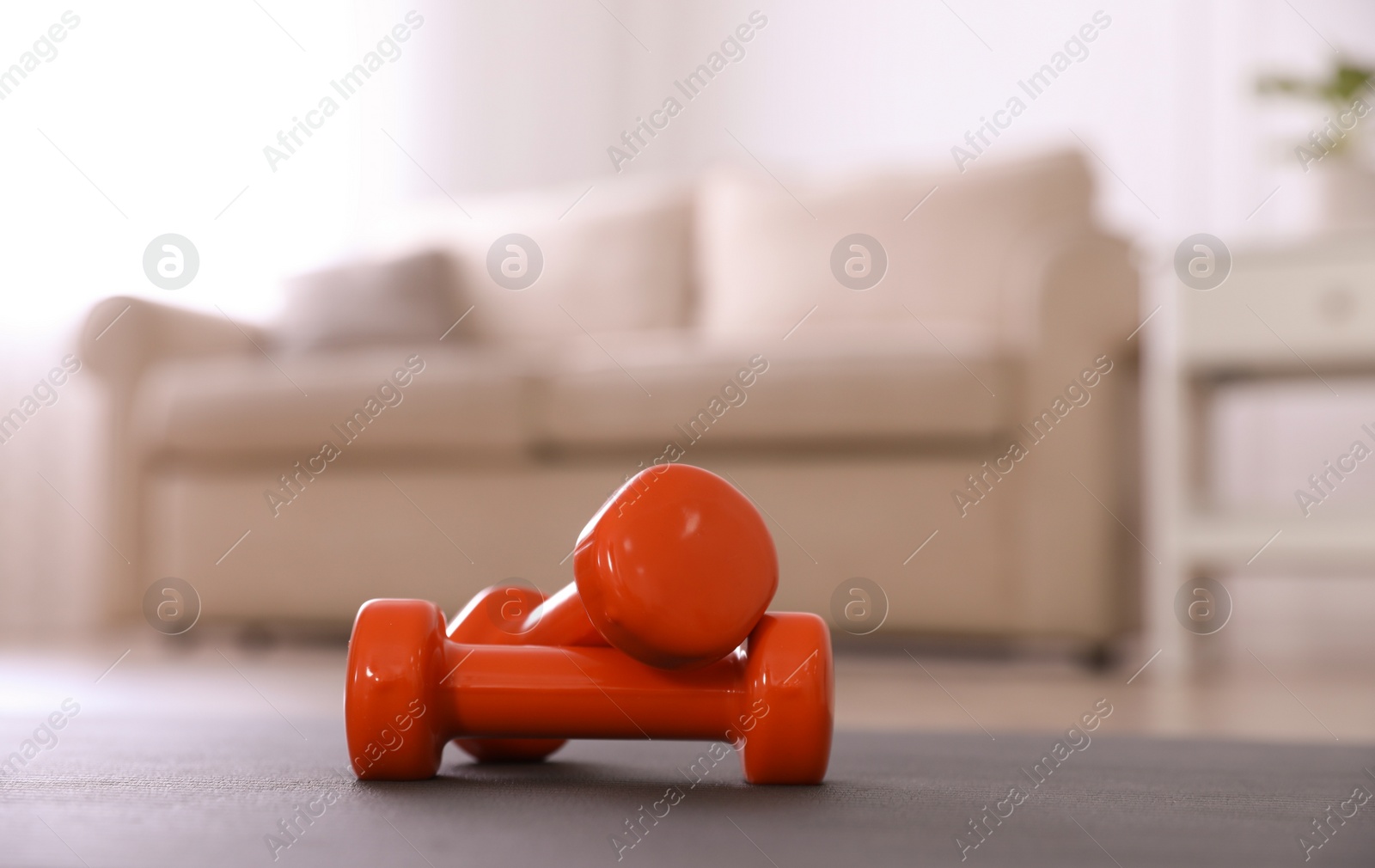 Photo of Orange dumbbells on floor in room. Home fitness