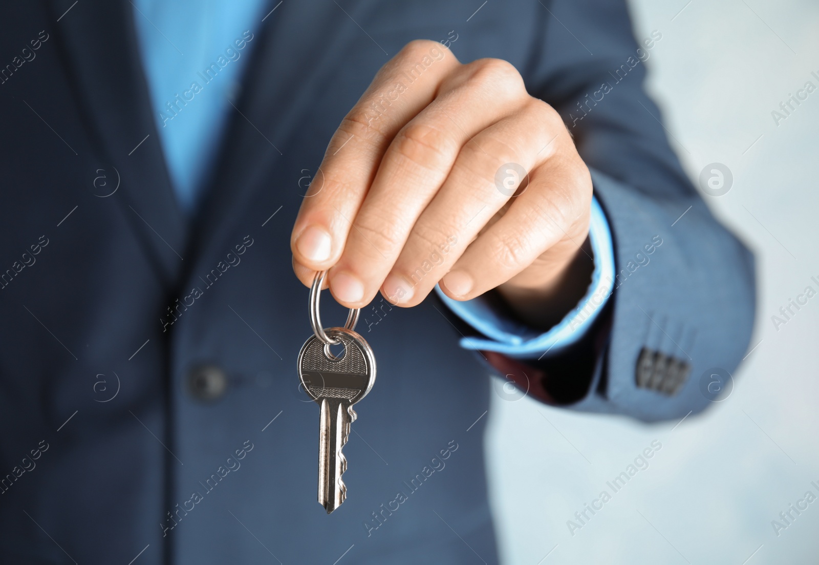 Photo of Young man holding key on color background, closeup