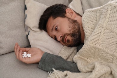 Depressed man with antidepressants lying on bed