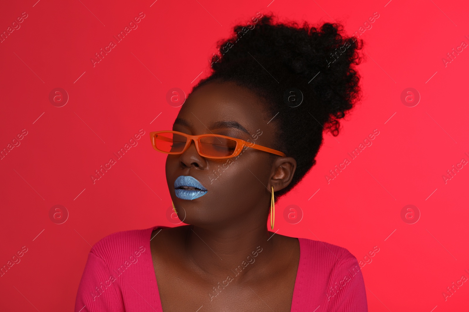 Photo of Fashionable portrait of beautiful woman with stylish sunglasses on coral background