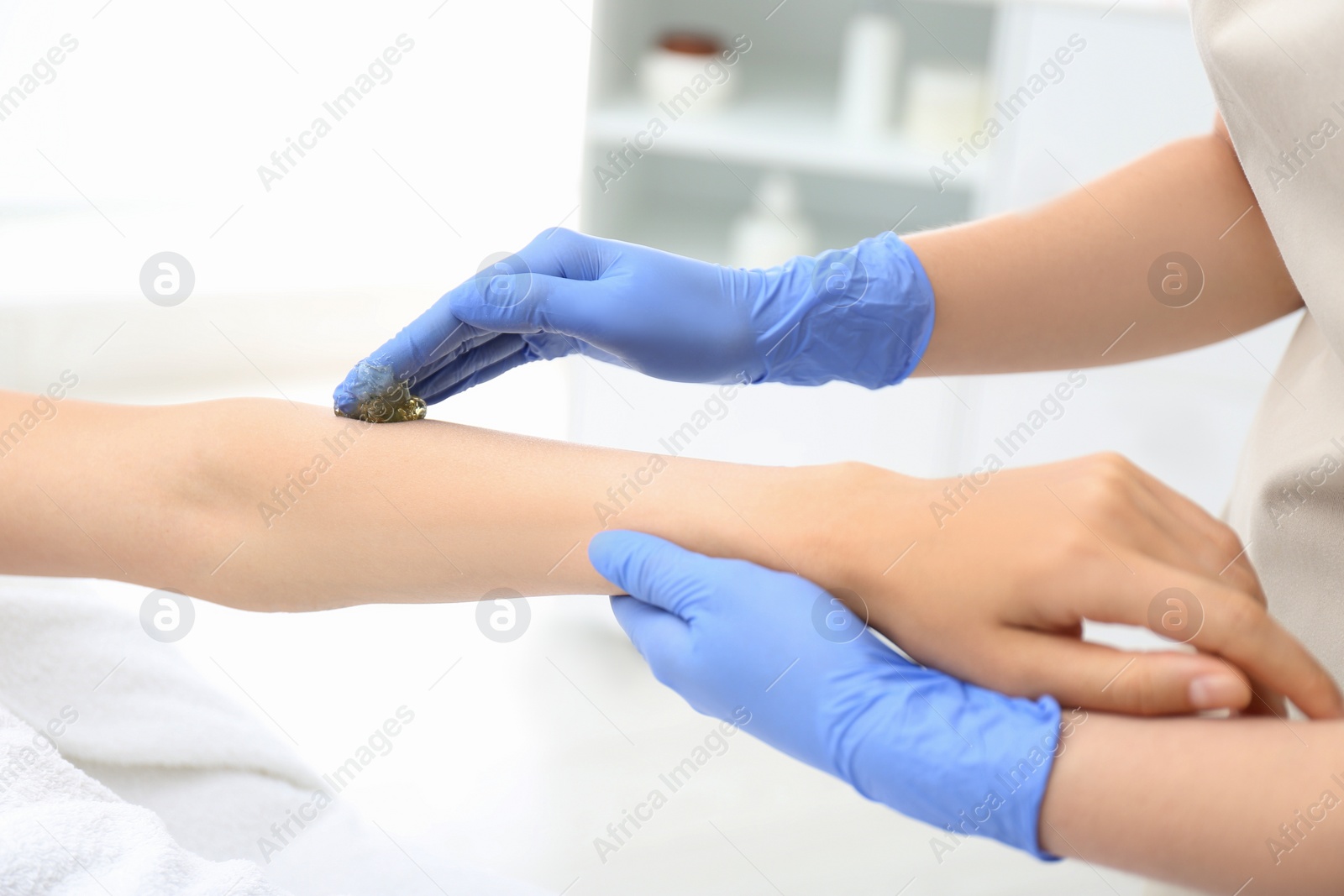 Photo of Woman getting wax epilation of arm in salon, closeup