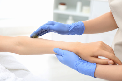 Woman getting wax epilation of arm in salon, closeup