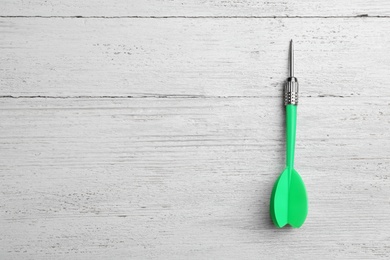 Green dart arrow on white wooden table, top view with space for text