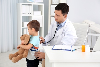 Children's doctor examining little patient with stethoscope in hospital