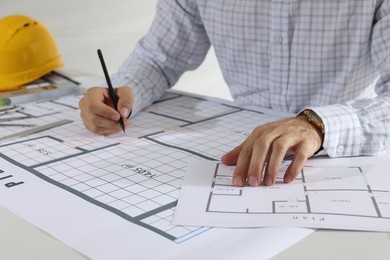 Photo of Architect working with construction drawings indoors, closeup