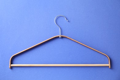 Photo of One wooden hanger on blue background, top view