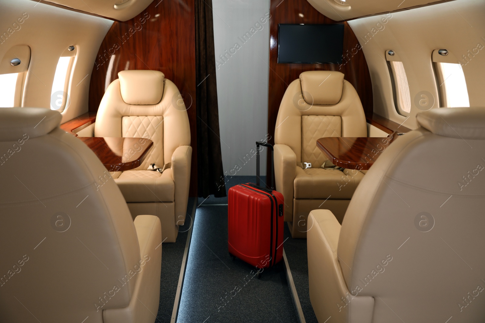 Image of Airplane cabin with red suitcase. Air travel