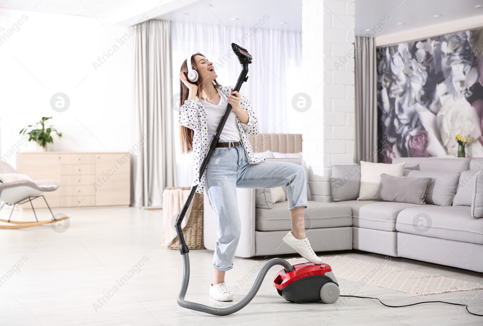 Photo of Young woman having fun while vacuuming at home