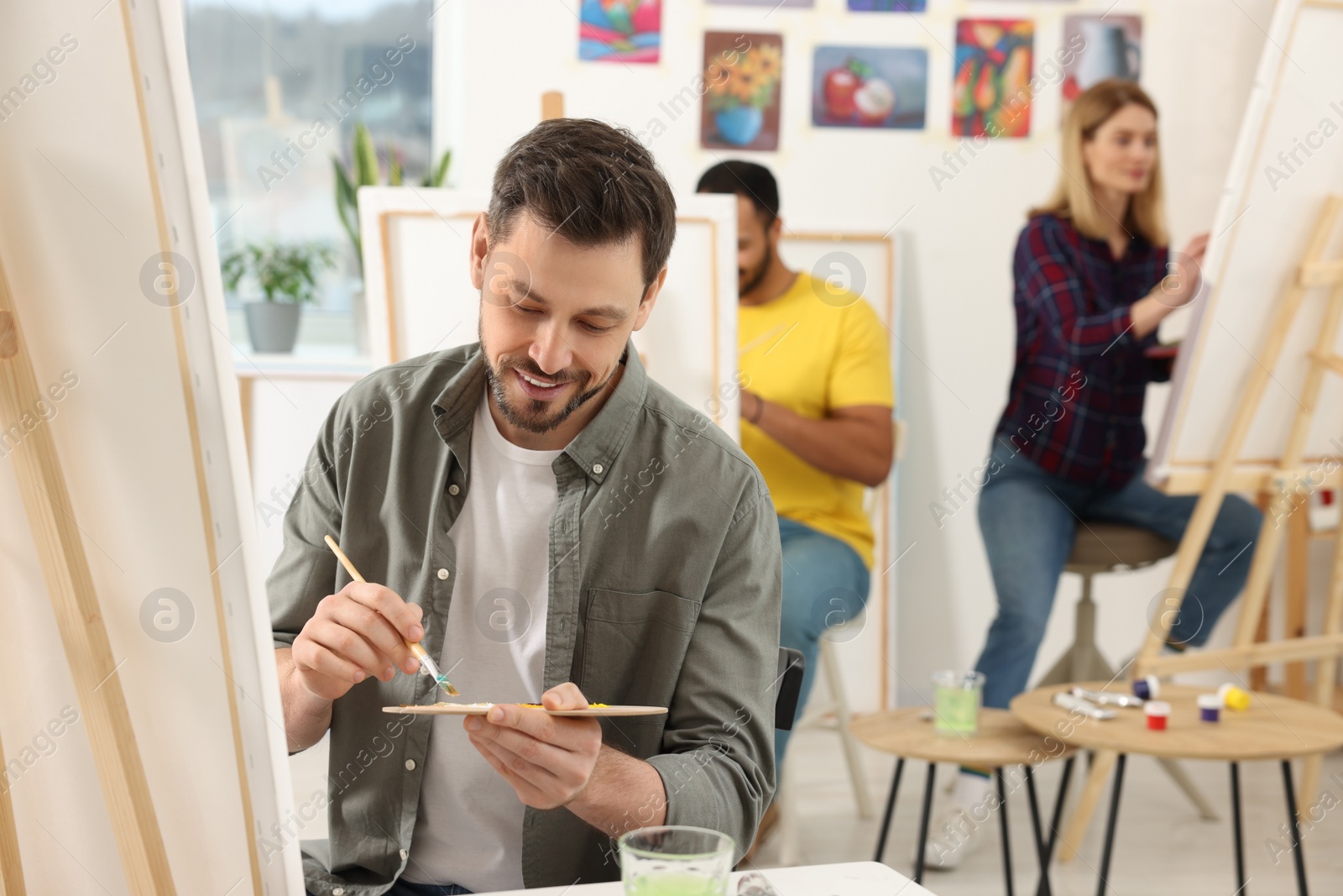 Photo of Group of students attending painting class in studio. Creative hobby