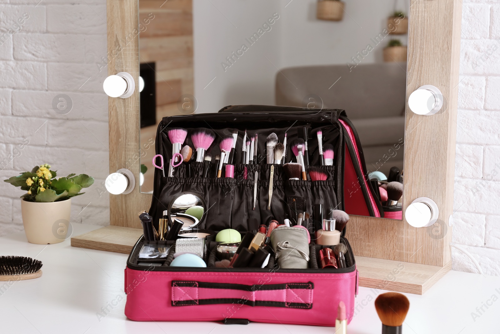 Photo of Beautician case with professional makeup products and tools on dressing table