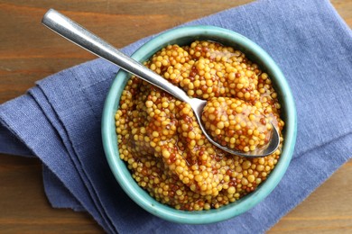 Photo of Whole grain mustard in bowl and spoon on wooden table, top view
