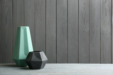 Photo of Stylish ceramic vases on grey wooden table. Space for text