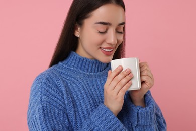 Photo of Happy young woman holding white ceramic mug on pink background