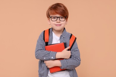 Cute schoolboy with book on beige background