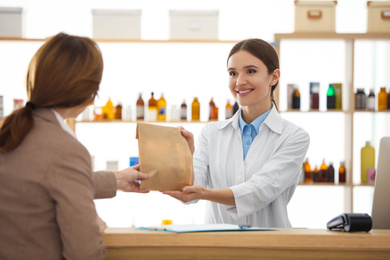Pharmacist giving medicine to customer in drugstore
