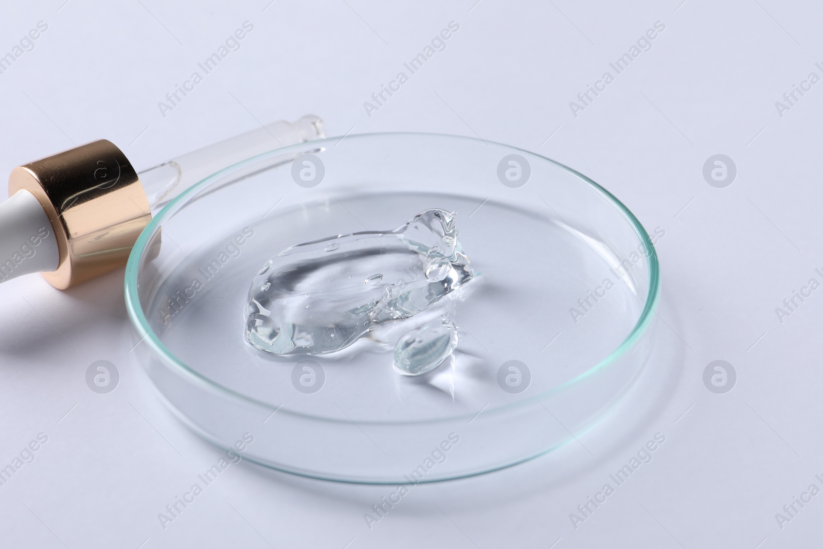 Photo of Petri dish with cosmetic serum and pipette on white background, closeup
