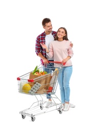 Young couple with full shopping cart on white background