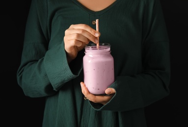 Photo of Woman holding fig smoothie on black background, closeup