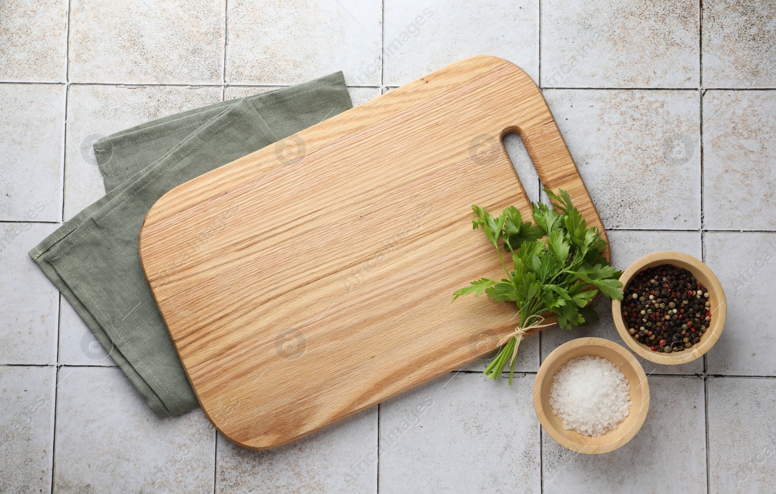 Photo of Cutting board, salt, pepper and parsley on white tiled table, flat lay. Space for text