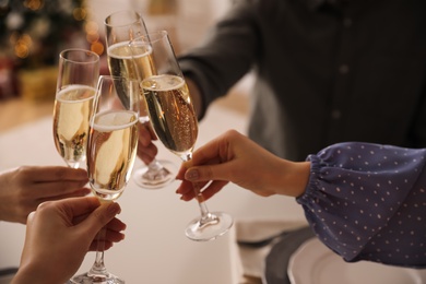 People clinking glasses with champagne at home, closeup