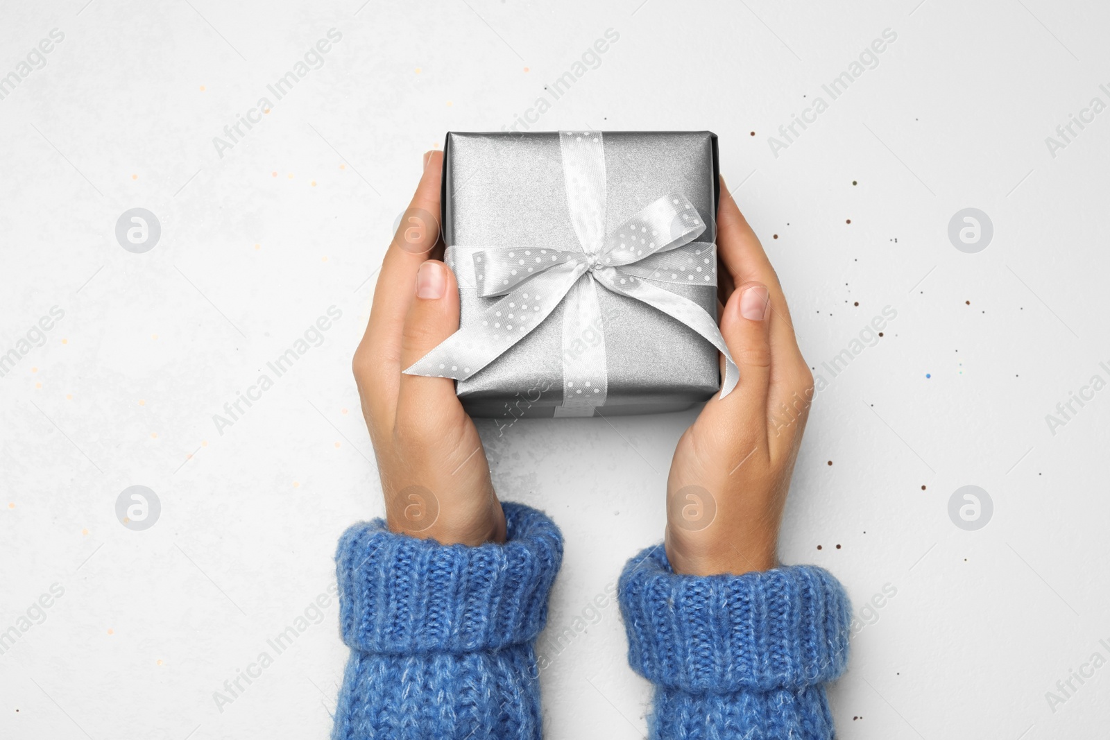 Photo of Young woman holding Christmas gift on white background, top view