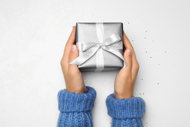 Photo of Young woman holding Christmas gift on white background, top view