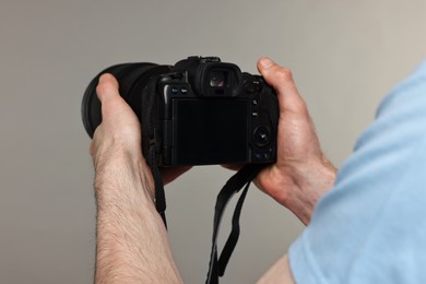 Photographer holding camera on grey background, closeup