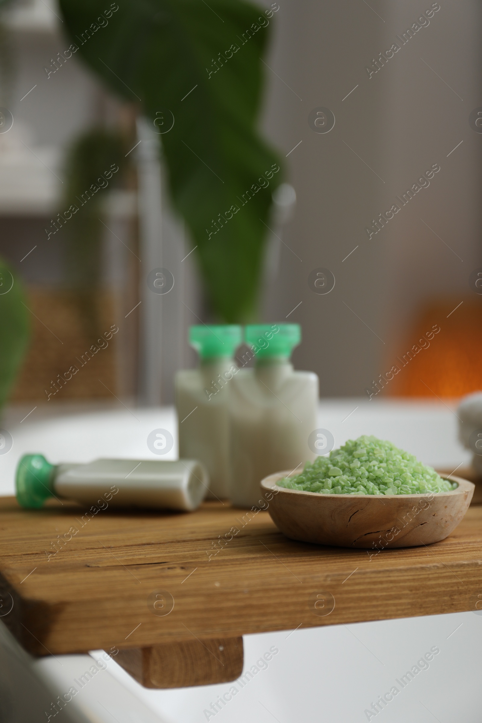 Photo of Wooden tray with cosmetic products and sea salt on bath tub in bathroom, closeup