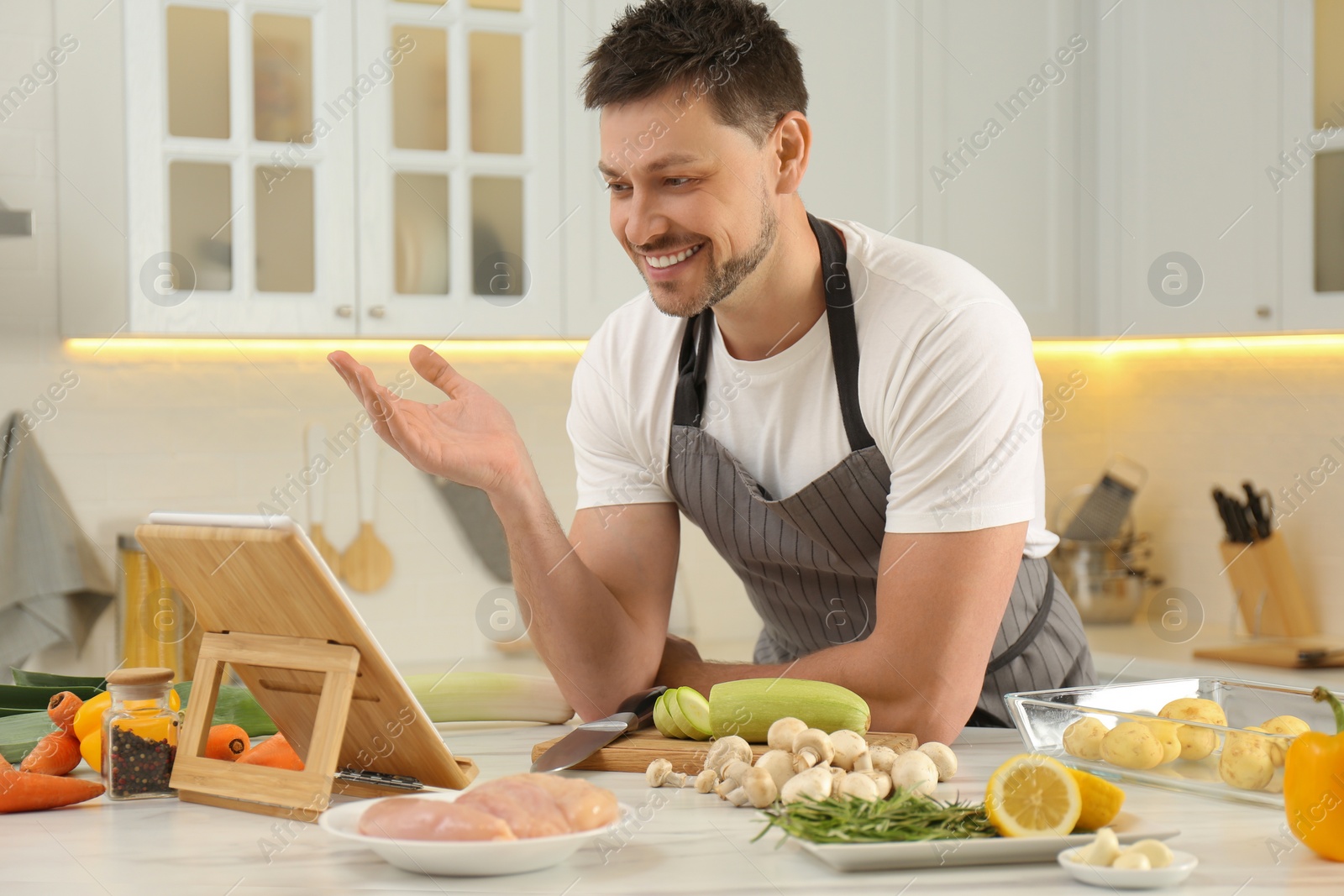Photo of Man watching online cooking course via tablet in kitchen