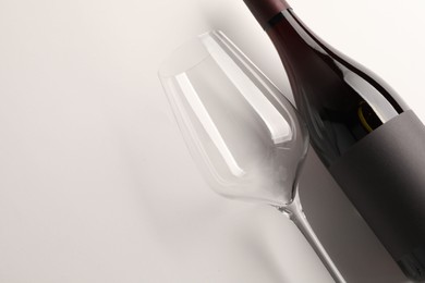 Bottle of tasty red wine and glass on white background, flat lay. Space for text