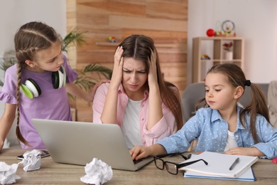 Children disturbing stressed woman in living room. Working from home during quarantine