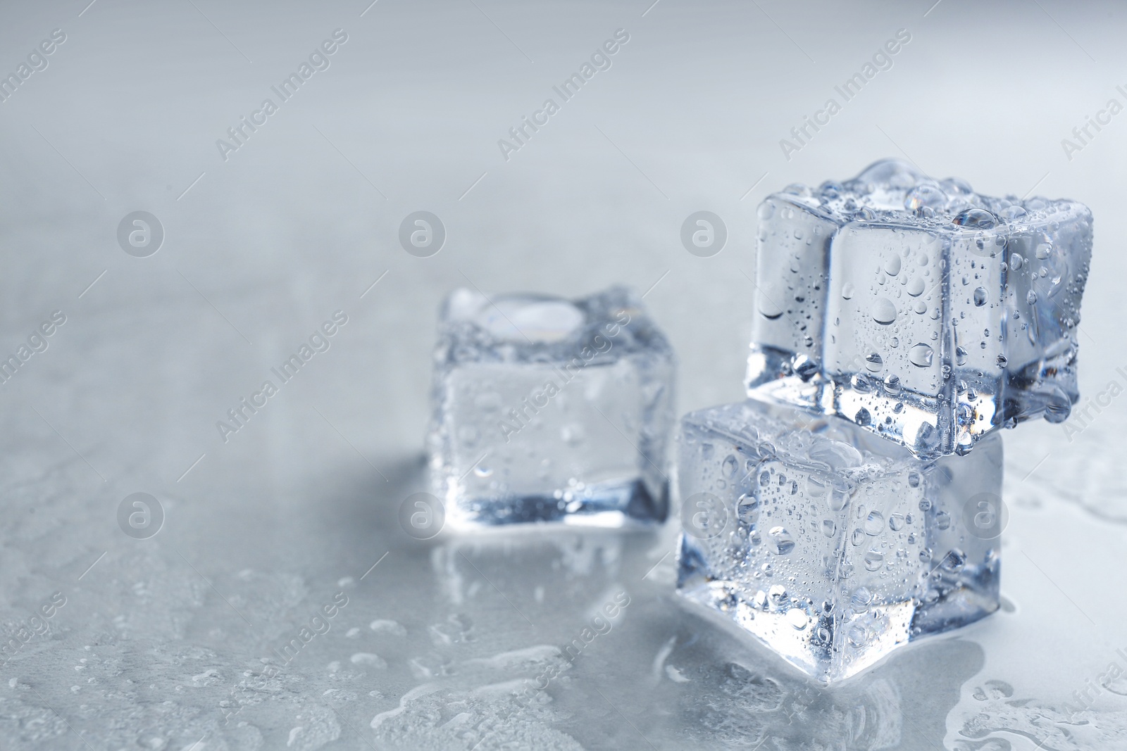 Photo of Crystal clear ice cubes on grey background, closeup. Space for text