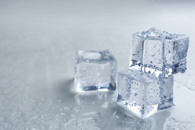 Photo of Crystal clear ice cubes on grey background, closeup. Space for text
