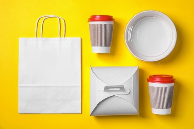 Different containers for mock up design on yellow background, flat lay. Food delivery service