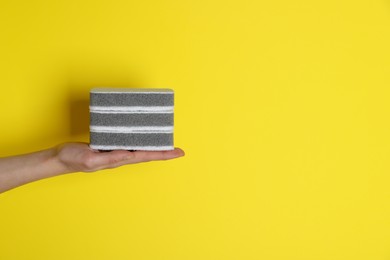Woman holding sponges on yellow background, closeup. Space for text