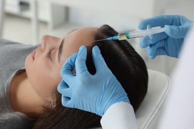 Photo of Trichologist giving injection to patient in clinic, closeup