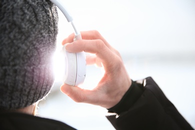 Photo of Young man listening to music with headphones outdoors, closeup