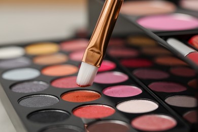 Photo of Colorful eyeshadow palette with brush, closeup view