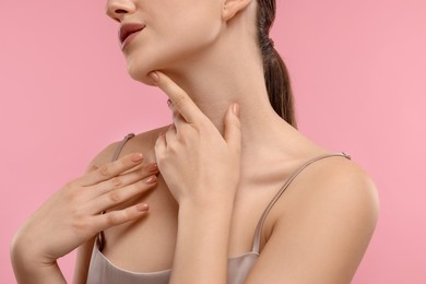 Woman touching her neck on pink background, closeup