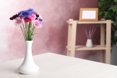 Photo of Bouquet of beautiful cornflowers in vase on white wooden table at home. Space for text