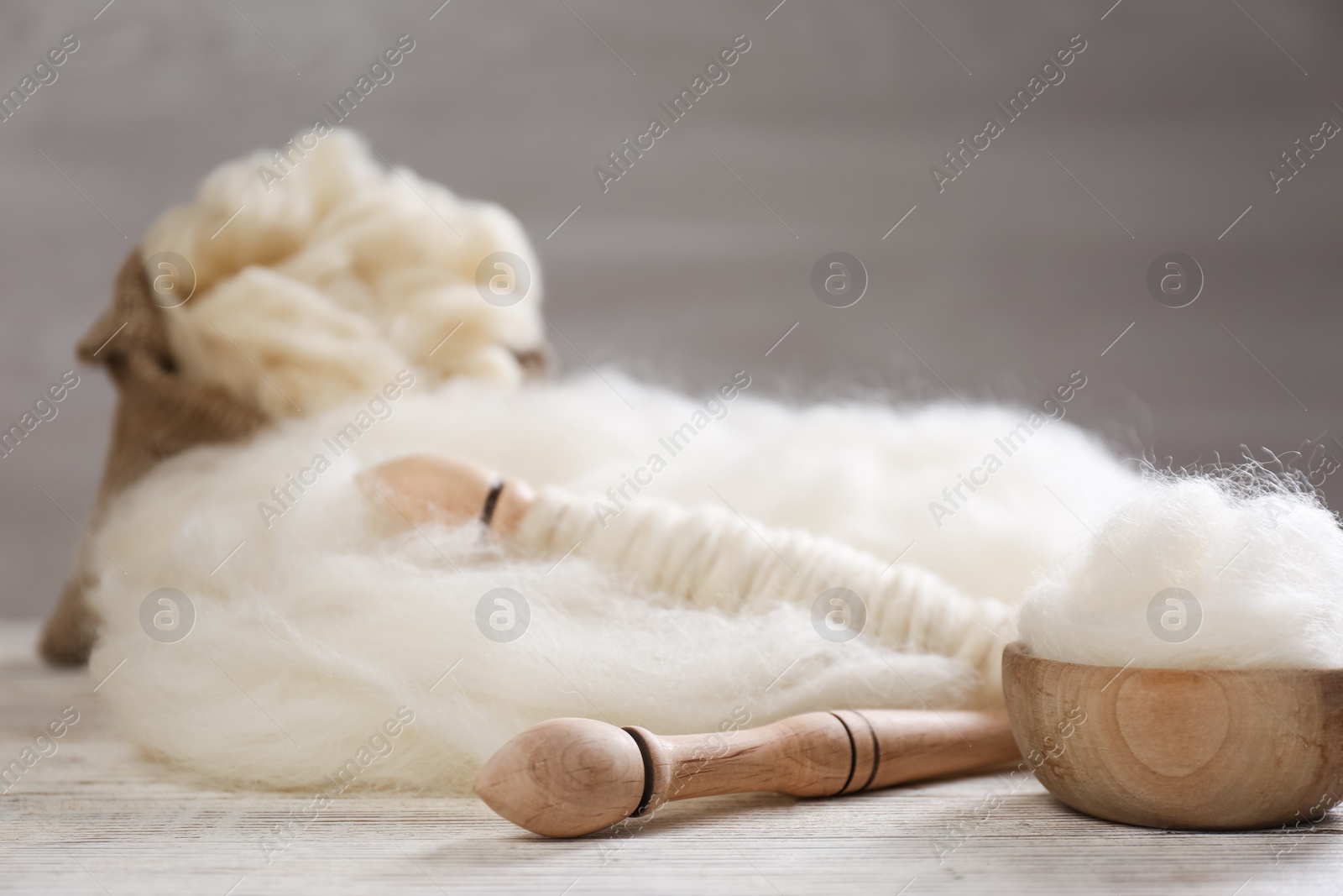 Photo of Soft white wool and spindles on wooden table. Space for text