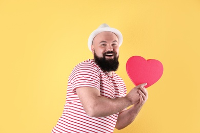 Emotional man with heart shaped box on color background