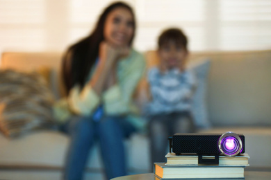 Young woman and her son watching movie at home, focus on video projector