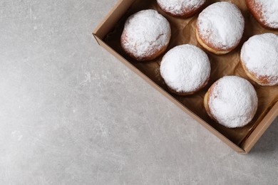 Photo of Delicious buns with powdered sugar in box on light grey table, top view. Space for text